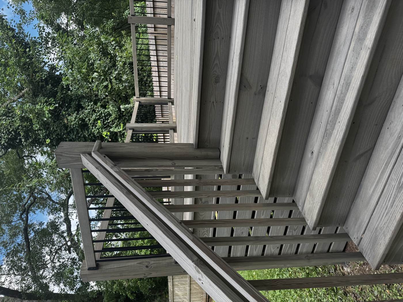 Gray stained deck stairs with black metal spindles