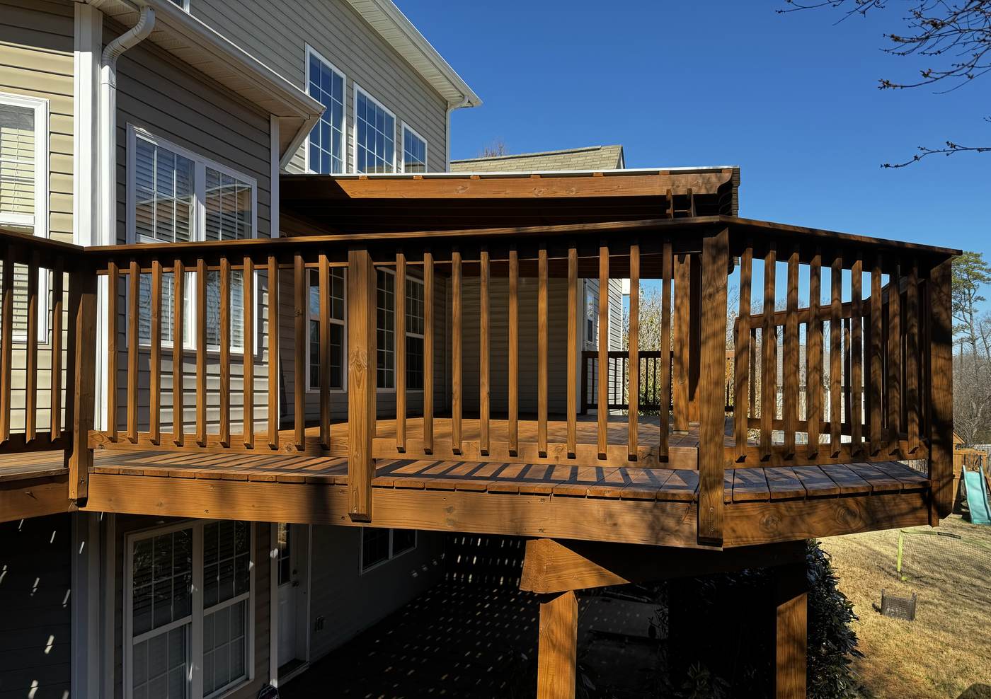 Warm stained deck leading toward a house