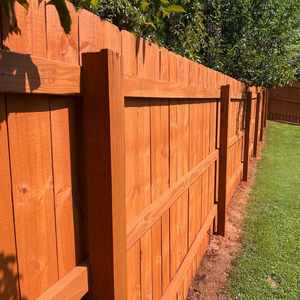 Cedar-toned dog-ear privacy fence receding down a yard